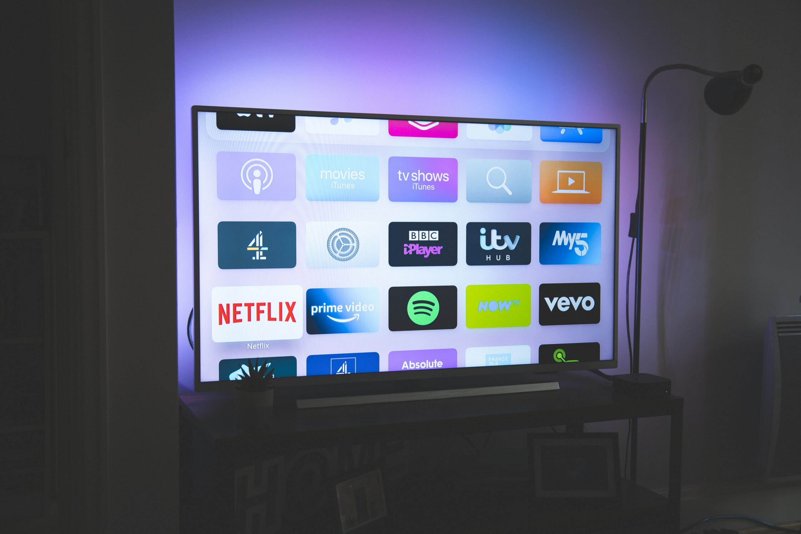 Streaming service logos on smart TV screen - black flat screen tv turned on showing game