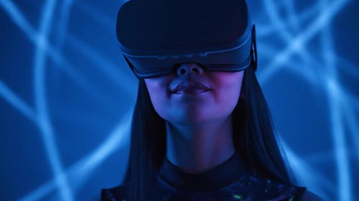 digital artist wearing augmented reality headset - Young woman uses virtual or augmented reality glasses in magic ...